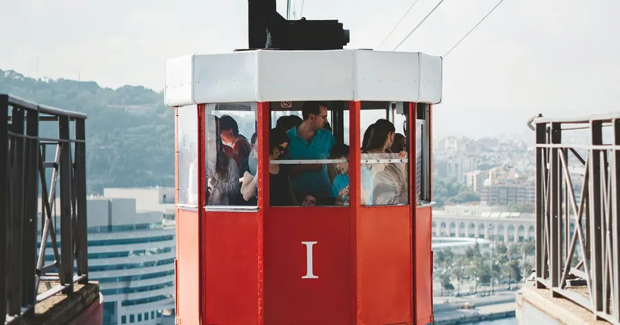 Eine rote historische Kabine der Hafenseilbahn an ihrer Station, dahinter die ausgebreitete Stadt